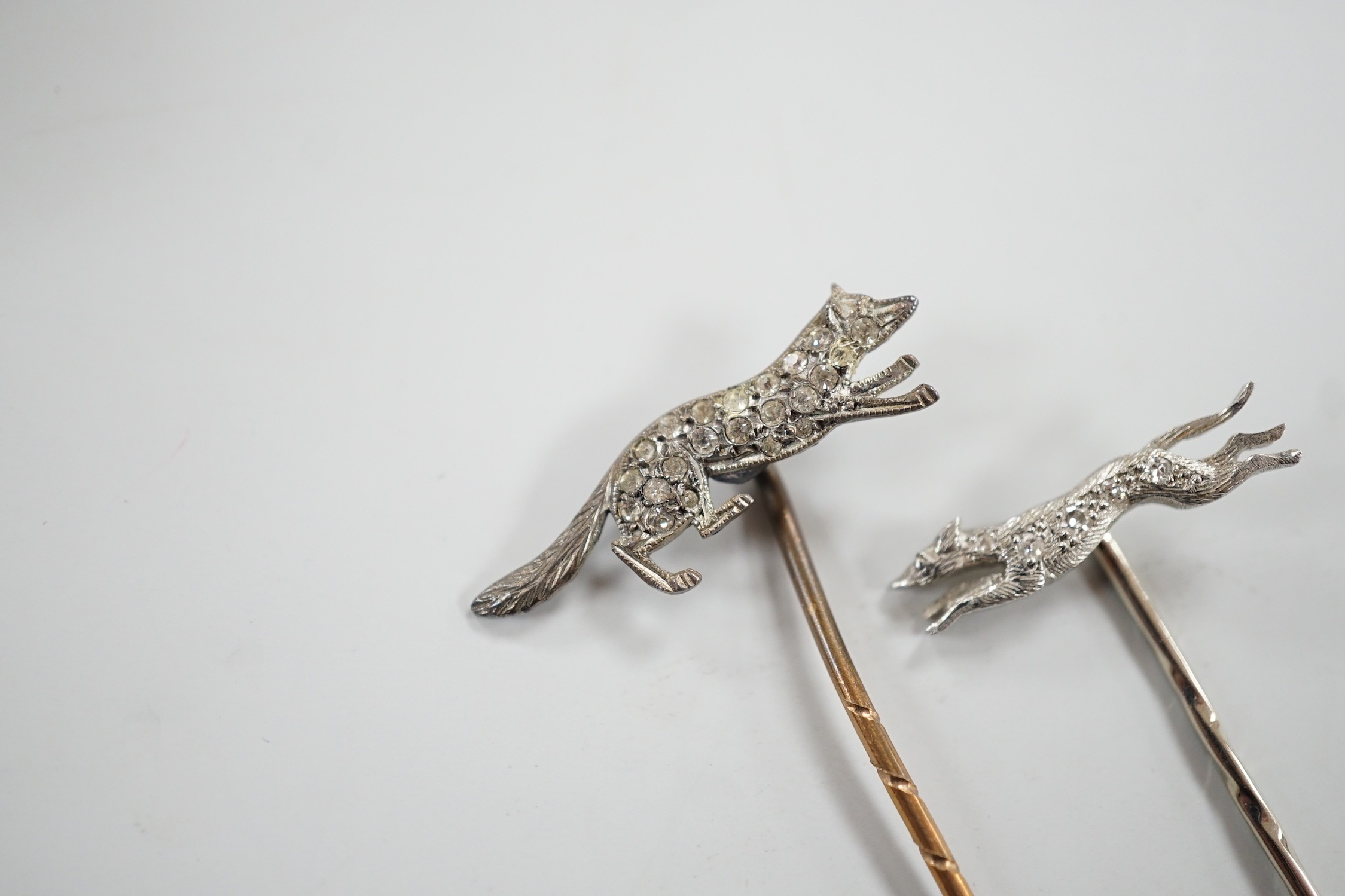 A mid 20th century white metal and diamond chip set hound stick pin, 57mm, in Asprey box and a similar paste set fox stick pin.